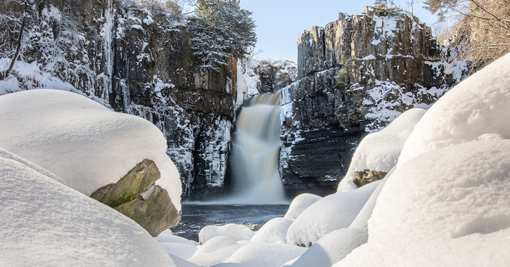 view of High Force Waterfall on a clear winter 's day covered in white crisp snow